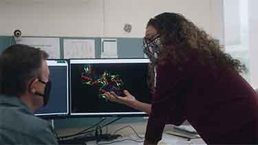 Mona Singh with a colleague speaking in front of a computer screen