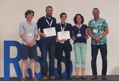 Andy Zeng standing on stage with co-author Alberto Rodriquez receiving the Best Systems Paper Award at the RSS conference.