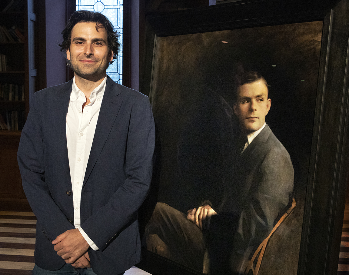 Artist Jordan Sokol standing with the portrait of Alan Turing.